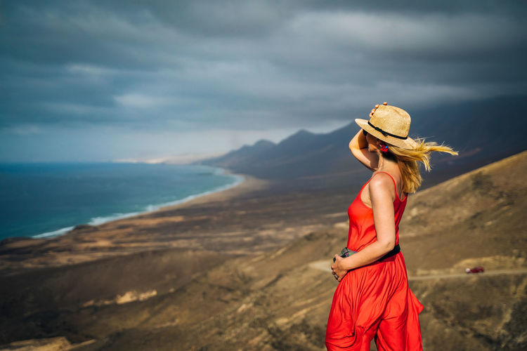 Woman standing on cliff against sky