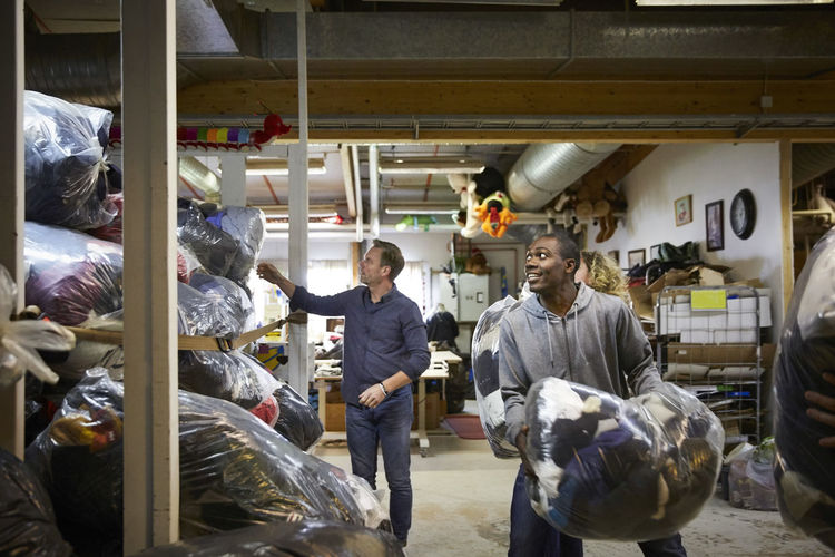 Coworkers stacking plastic sacks in warehouse
