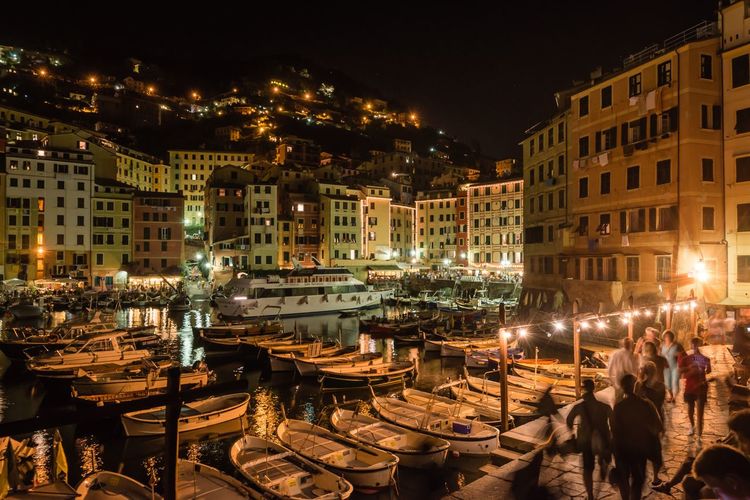 People by boats on footpath in camogli at night