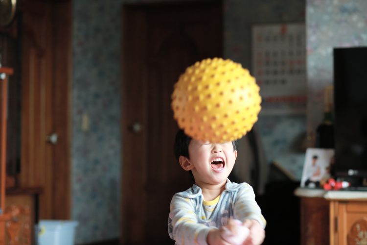 Happy boy playing with ball at home