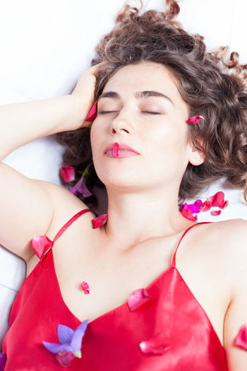 High angle view of beautiful woman lying with petals on bed