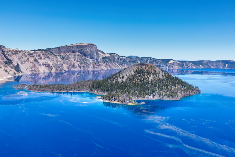 This specifiic crater lake blue. wizard island in the blue water of the crater lake.