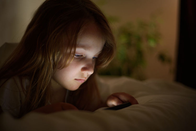 Girl using smart phone on bed at home