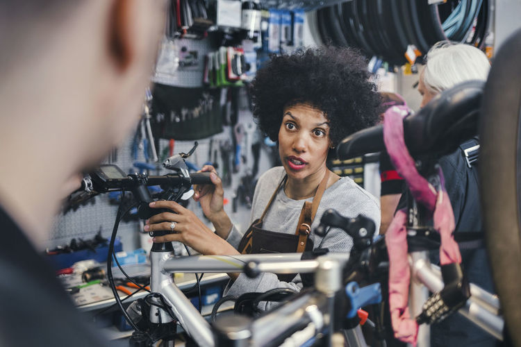 Female mechanic communicating with male customer in bicycle repair shop