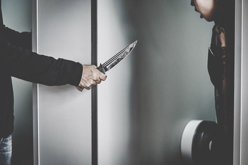 Cropped image of thief showing knife to woman