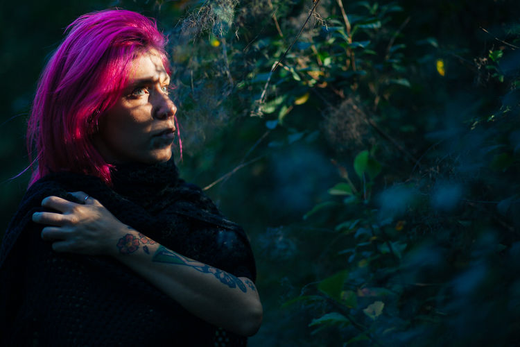 Thoughtful woman with dyed hair by tree
