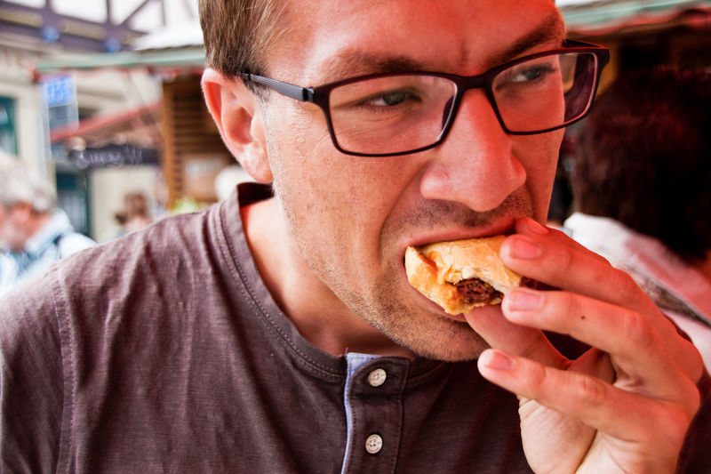Close-up of young man eating hamburger outdoors