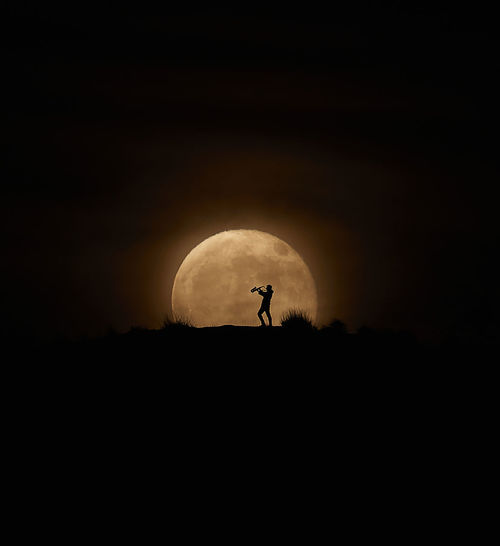 Silhouette man against moon in sky at night