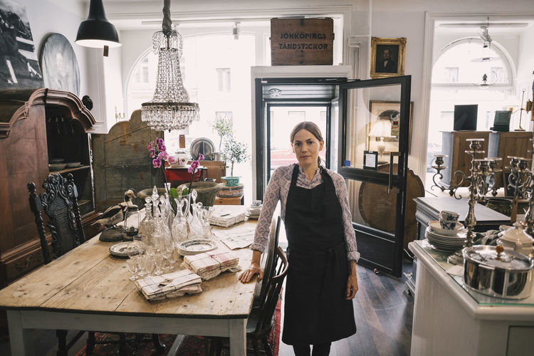 Portrait of confident female owner standing in antique store