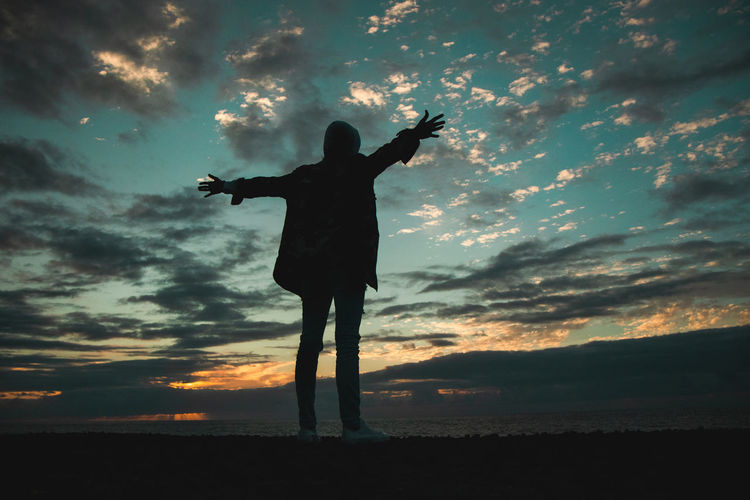 Silhouette man standing on shore against sky during sunset