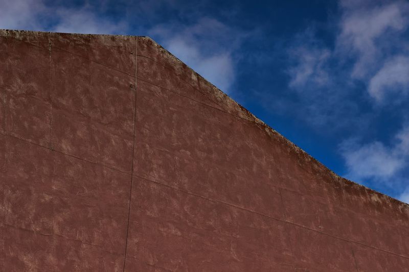 Low angle view of wall against cloudy sky