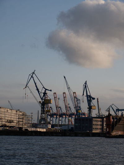 Cranes at commercial dock against sky