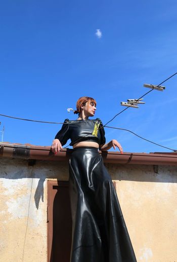 Low angle view of woman standing against blue sky