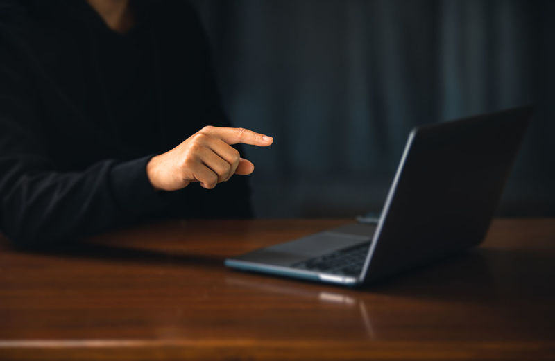 Midsection of man using laptop at table