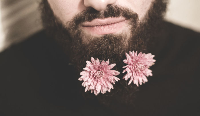 Midsection of man beard with pink flowers