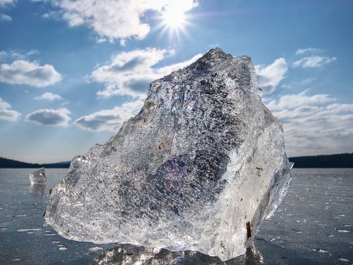 Beautiful transparent piece ice of lake against dark blue sky and bright sun.