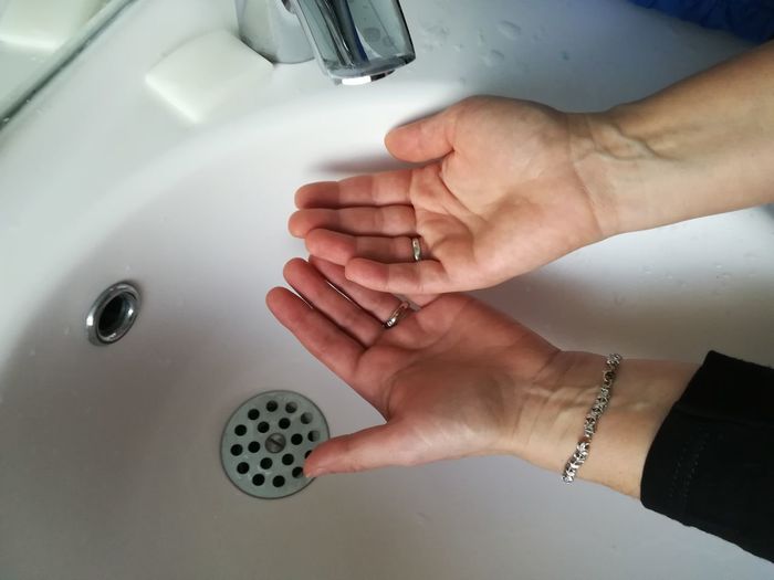 Cropped woman cupping hand below bathroom faucet 