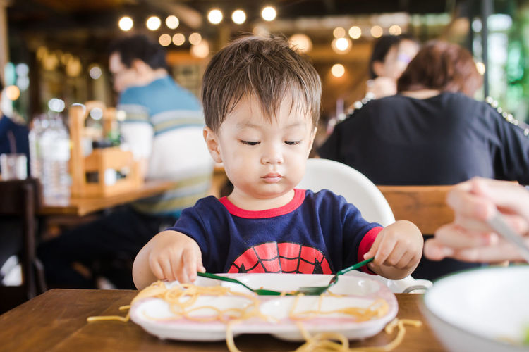 Cute baby boy having meal at restaurant