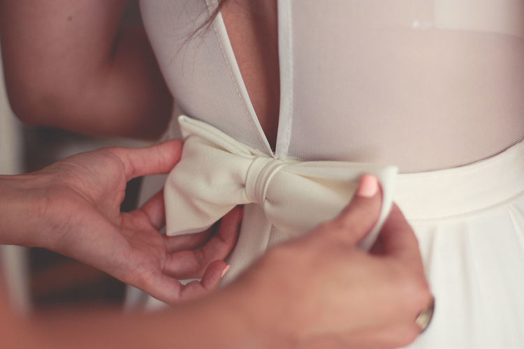 Cropped hands of bridesmaid adjusting bride dress