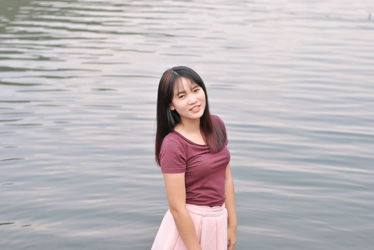 Portrait of smiling young woman standing in water