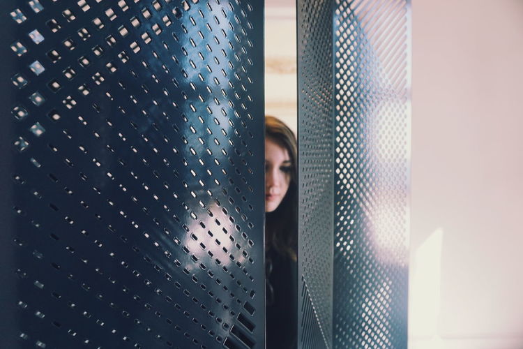 Close-up of young woman seen through metal