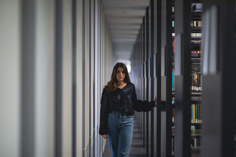 Portrait of young woman standing in library