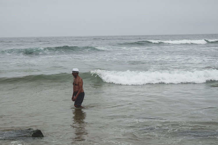 Rear view of man standing in sea against sky