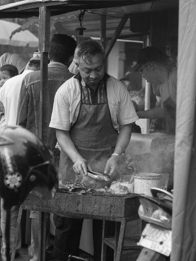 Mature man barbecuing at market stall