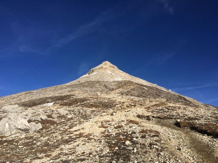Low angle view of sand dunes against clear blue sky