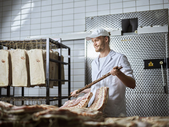 Butcher arranging fresh raw meat in factory
