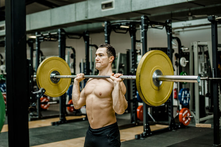 Strong man doing weightlifting exercise at gym