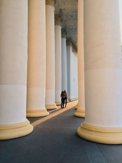 Friends standing amidst columns in colonnade