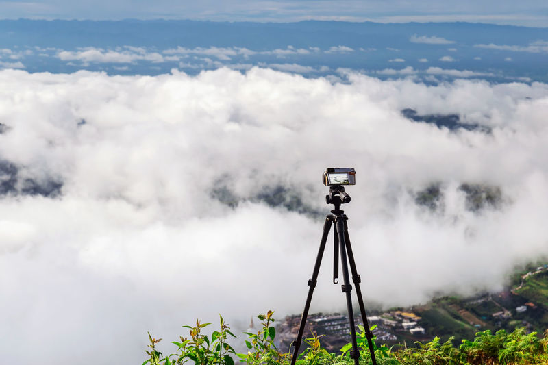 Set a digital camera on a tripod to capture the view of the sky, clouds and mountains.