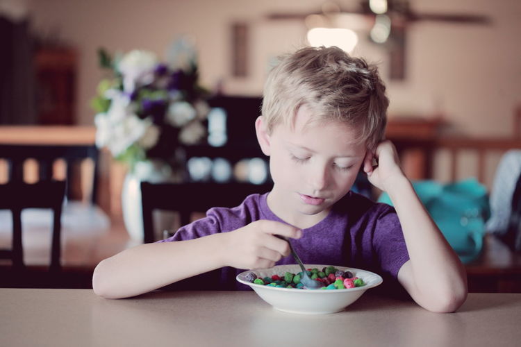 Boy looking at breakfast cereal on table at home
