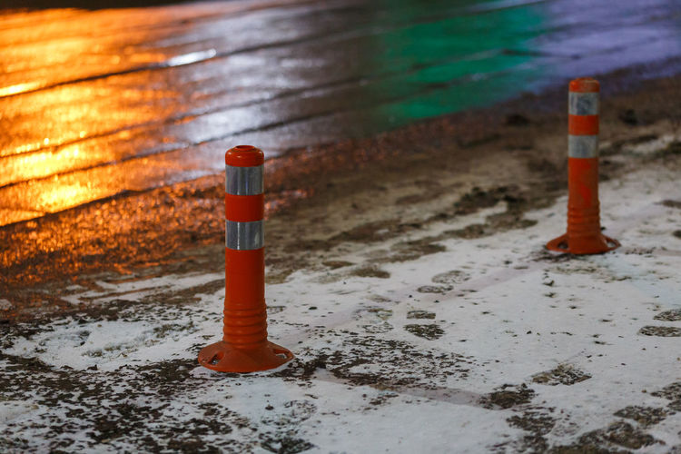 Traffic cones at winter night city with snow and footprints - close-up with selective focus