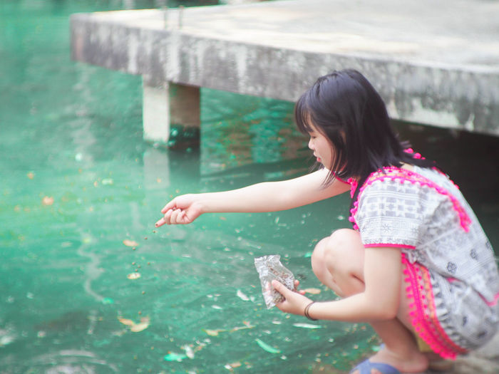 Woman spilling food in pond