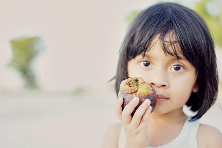 Close-up portrait of girl holding food while standing outdoors