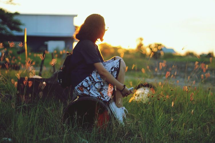 Woman standing on field at sunset