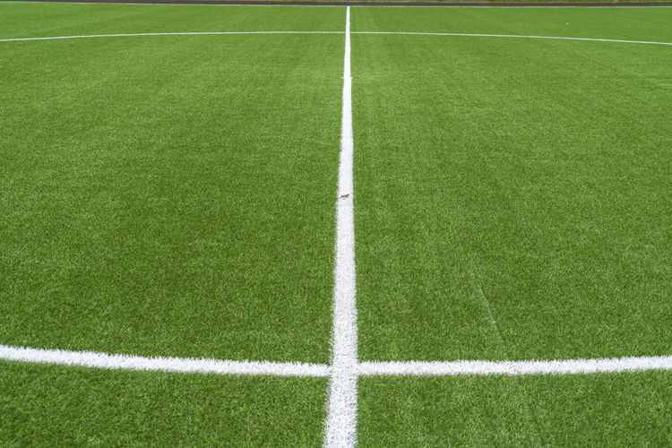 Green artificial grass soccer sports field with white stripe line.