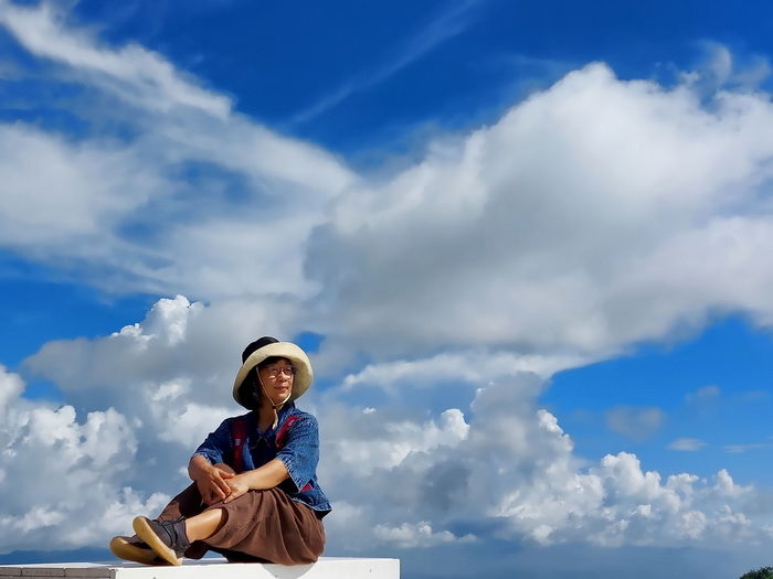 Low angle view of woman sitting on the stairs against sky