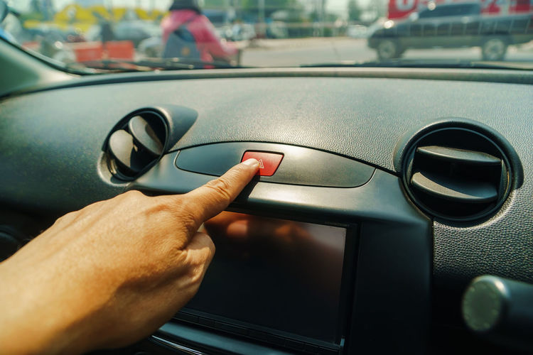 Cropped hand of person pressing button in car