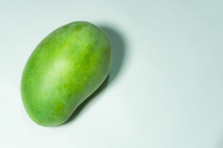 High angle view of green fruit over white background