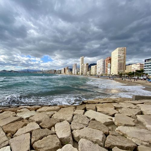 Sea by buildings against sky in city