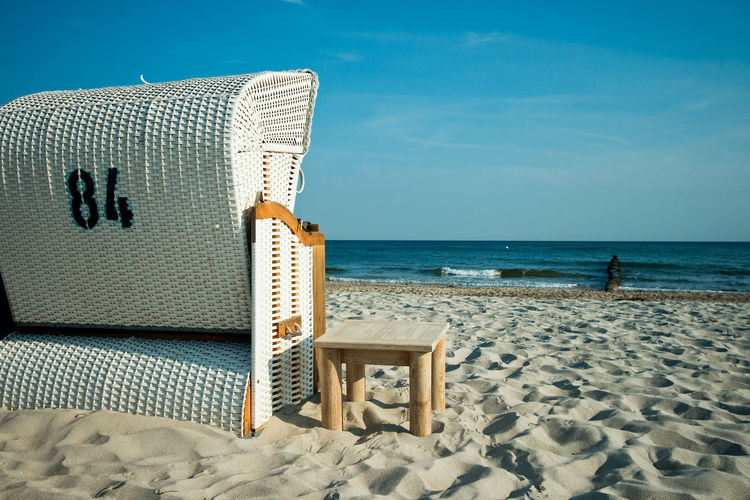 Hooded chairs on beach against sky