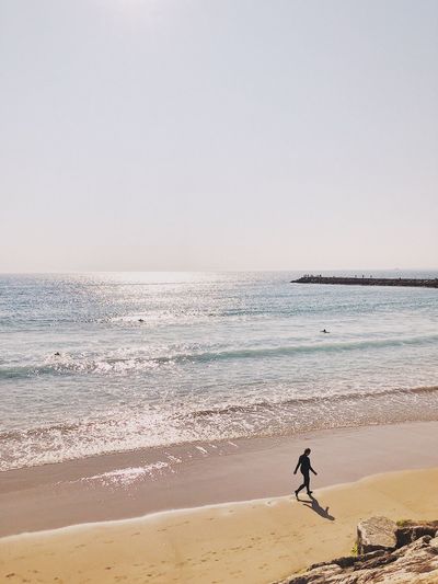 High angle view of man walking on beach against clear sky
