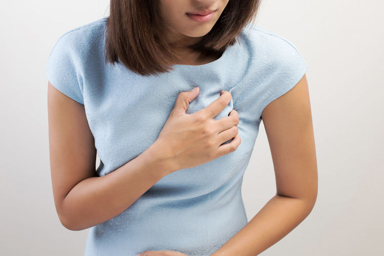 Midsection of woman with chest pain against white background