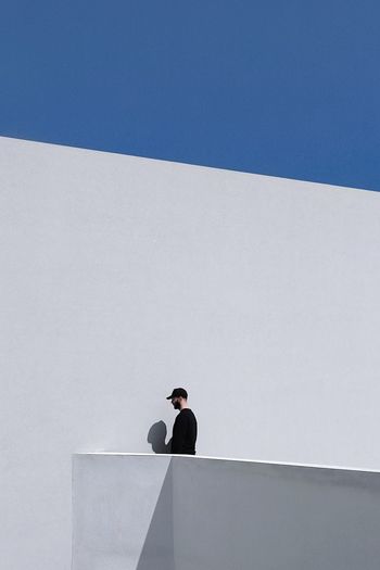 LOW ANGLE VIEW OF MAN STANDING AGAINST WALL