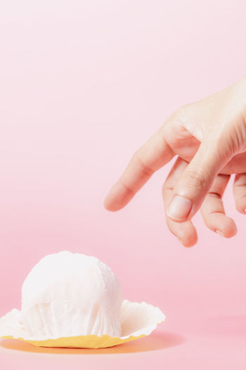 Close-up of hand holding pink over white background