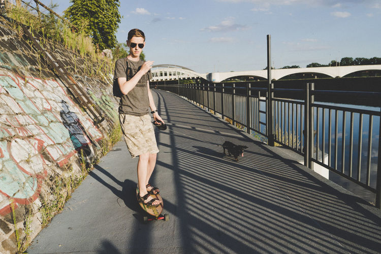 Portrait of young man skateboarding with dog 