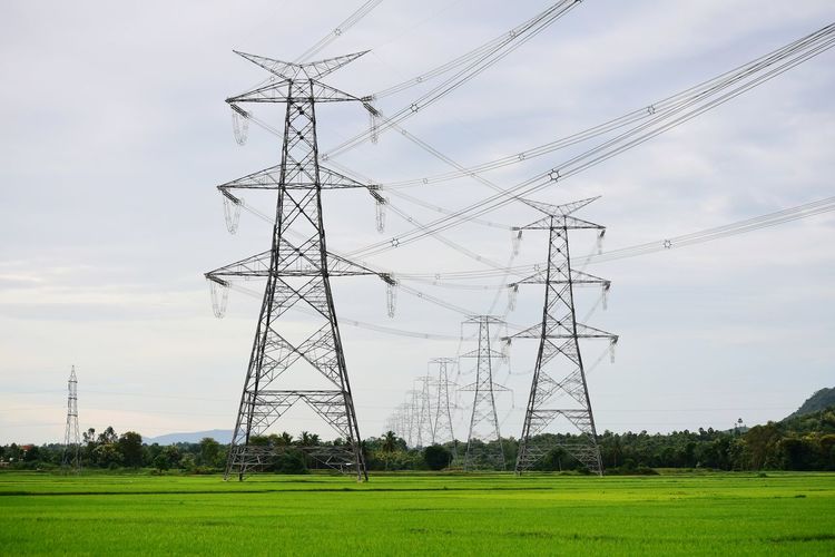Electricity pylon on field against sky